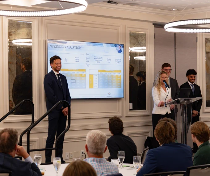 Presentation in progress at the RGIP showcase, with three Stetson students at a podium, smiling and presenting.