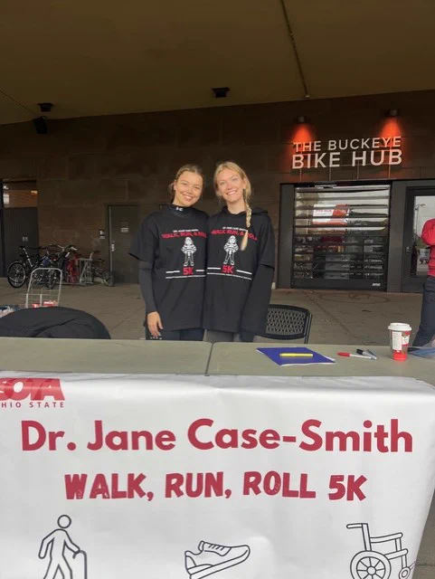 OT students, Amanda Burgei and Mallory Mitchell at the check in table at the Dr. Jane Case-Smith Walk, Run, Roll 5K
