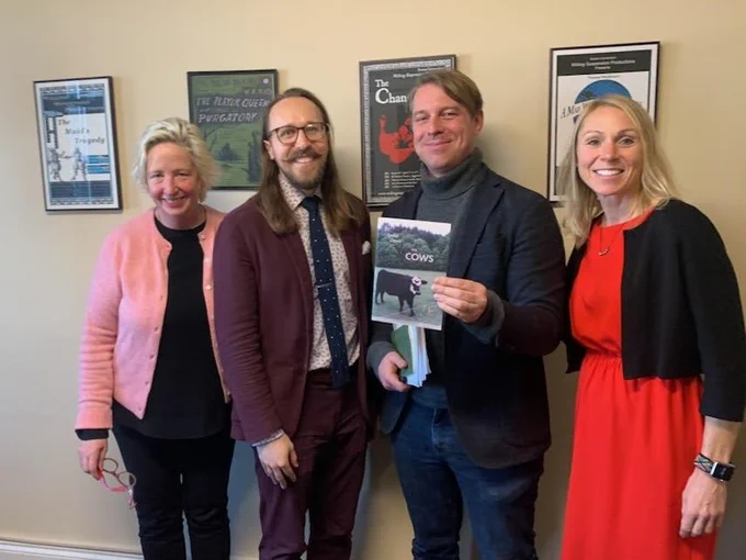 Photo of me with three members of my dissertation defense committee. Left to right: Anna Henchman, in a pink cardigan; me in a burgundy suit; Jonathan Foltz in a gray blazer and turtleneck; and Carrie Preston in a red dress. All smiling.
