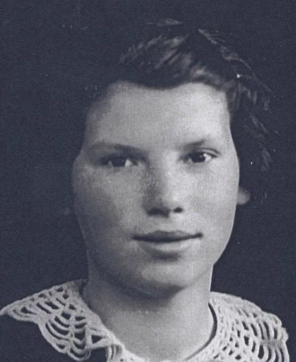 Black and white portrait of a young girl, displaying a slight smile and wearing a light-colored dress with a lace collar.