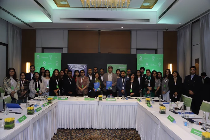 A large group of participants from government, industry, academia, and civil society stand together at the end of the roundtable, gathered behind a U-shaped conference table and event branding for the Duolingo English Test, USIBC, TQH, and Kaio, reflecting a shared commitment to reimagining testing and education partnerships in India’s digital future.
