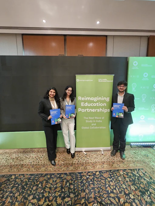 Three representatives from TQH stand in front of a green banner reading “Reimagining Education Partnerships: The Next Wave of Study in India and Global Collaboration,” each holding a copy of the new white paper, underscoring their shared commitment to expanding access through digital, AI-enabled testing and cross-border education partnerships.