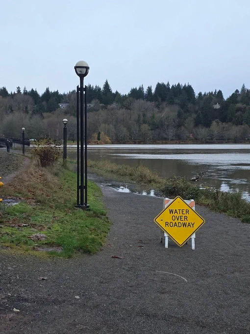 Capitol Lake flooded with water. A caution sign reads, "Water over roadway."