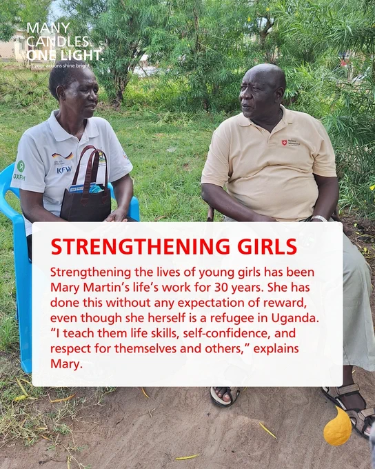 Zwei Männer sitzen auf blauen Stühlen und halten ein Schild mit der Aufschrift "Strengthening Girls" in der Hand.