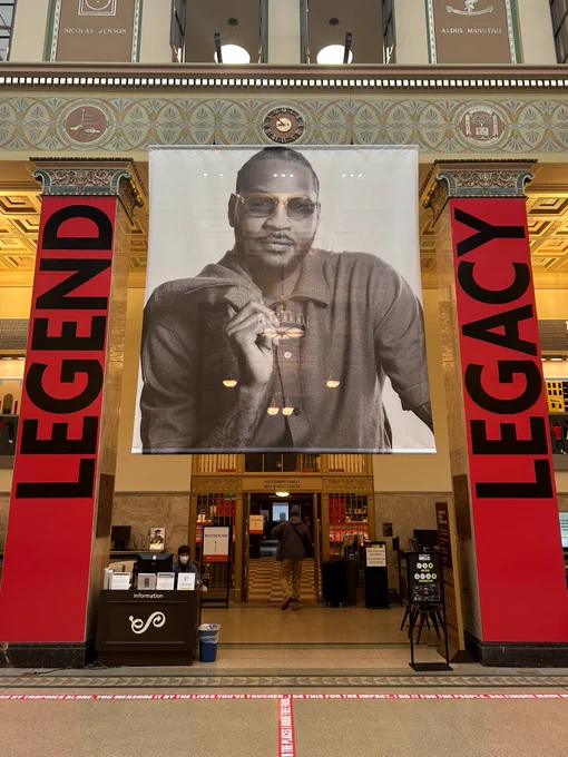 An image of Carmelo Anthony and two banners reading "Legend" and "Legacy" hang in the Enoch Pratt Free Library Central Branch.