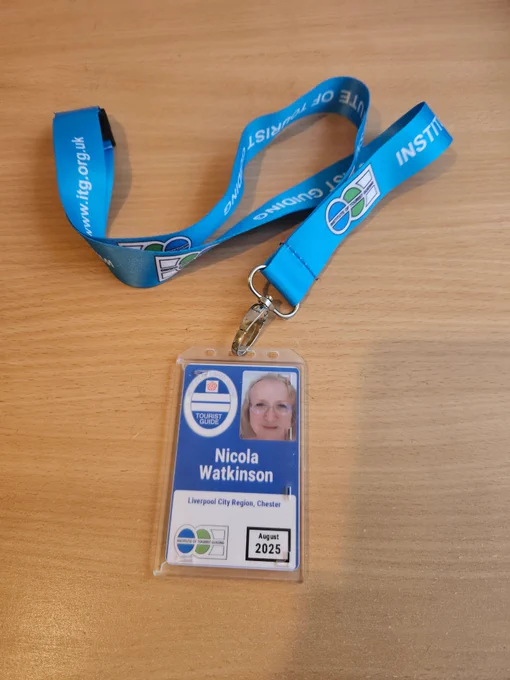 Blue lanyard and photo ID card of Nicola Watkinson on a beechwood background