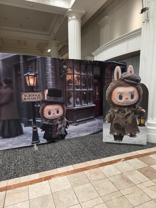 Labubus inexplicably dressed in Dickensian garbage in front of a Victorian London backdrop. Mind you these things are like five feet tall.