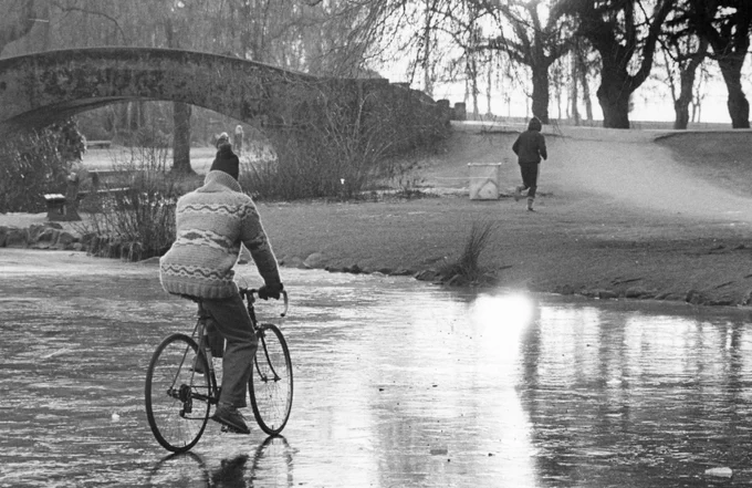 Black and white photo of a person on a bicycle riding over ice in Stanley Park, Vancouver.