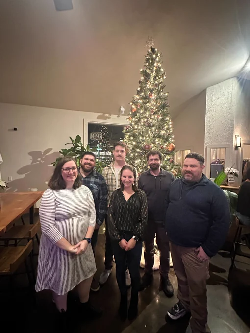 The Bytes.co client services team standing together in front of a Christmas tree