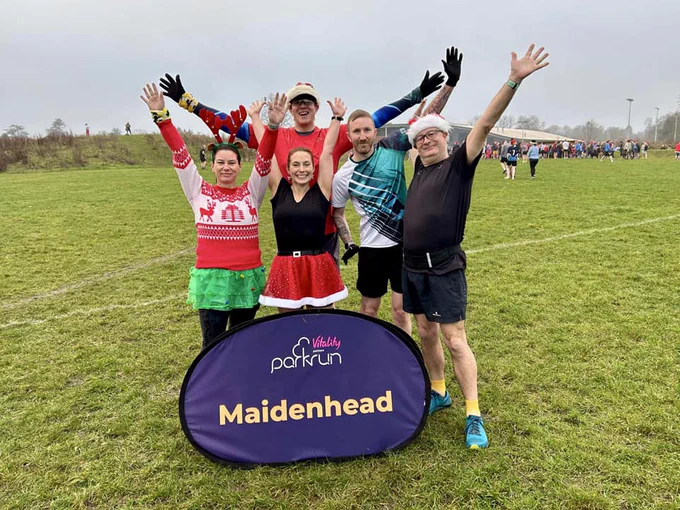 Image of group of parkrunners wearing Christmas clothing behind the Maidenhead parkrun sign