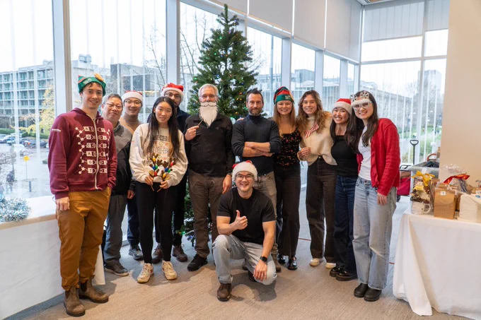 Members of the Kronstad lab are pictured in front of a festive tree, wearing fun festive decorations and smiling to camera. 