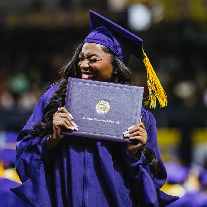 A graduate holds a Tennessee Tech diploma cover.