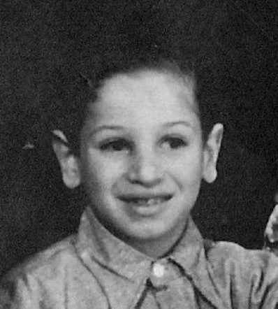 Black and white portrait of a young boy smiling at the camera, wearing a button-up shirt.