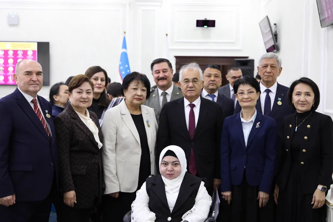 Group photo of officials and award recipients at a Human Rights Day ceremony, with national symbols in the background.