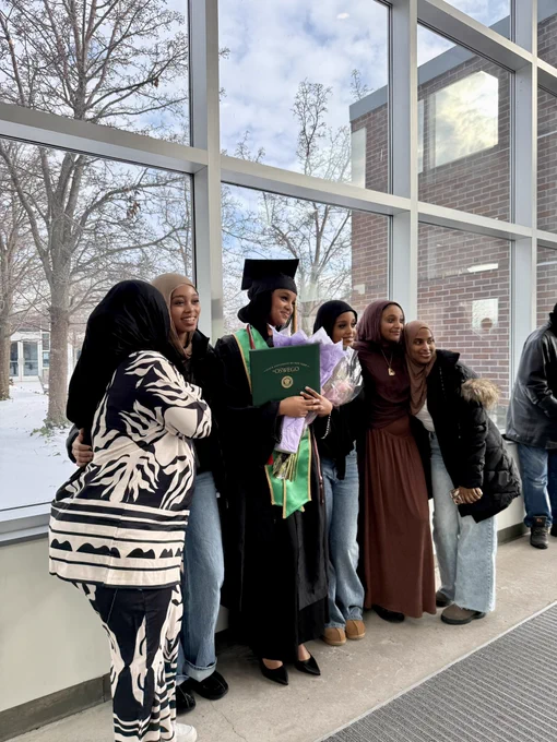 A SUNY Oswego graduate takes a photo with family  in Marano Campus Center after commencement.