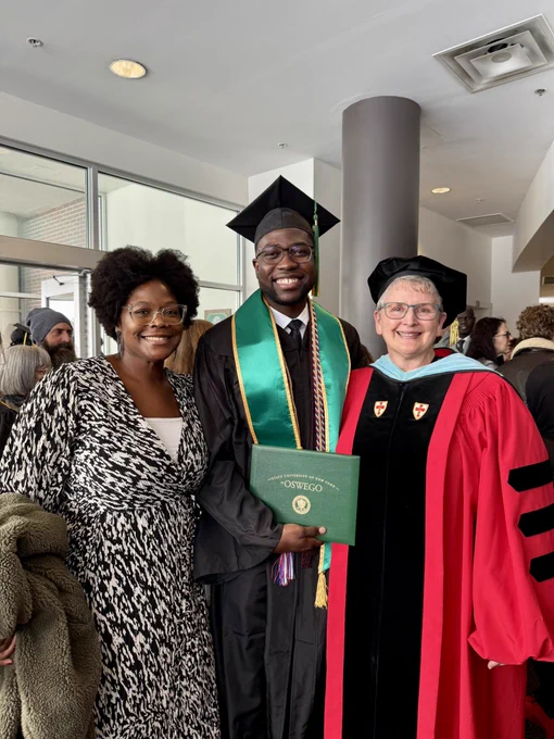 A SUNY Oswego graduate holding their diploma with their family member and professor in Marano Campus Center.