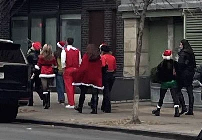 Young people in Christmas/Santa-related garb walking down a street in the East Village