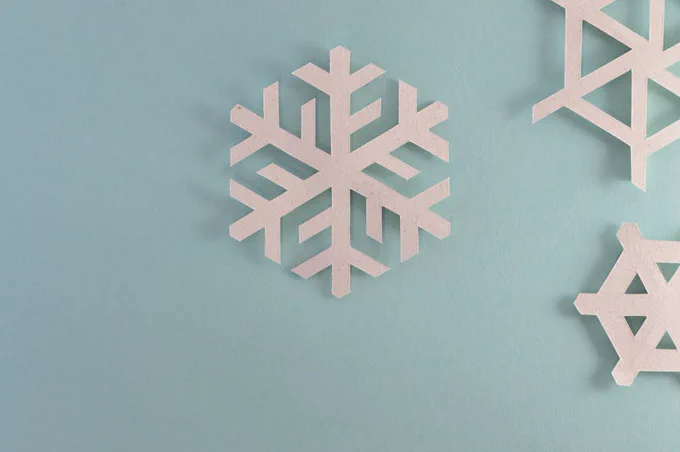 Elegant paper snowflakes on a pale blue background, perfect for winter or holiday decor.