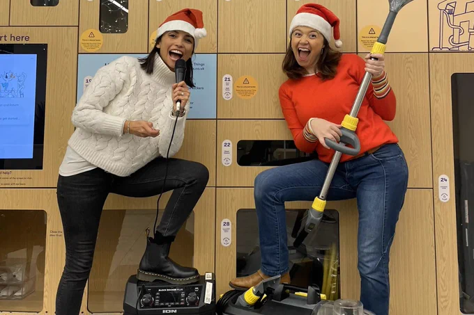 Two women posing happily in Santa hats at the Library of Things in Patch, Twickenham