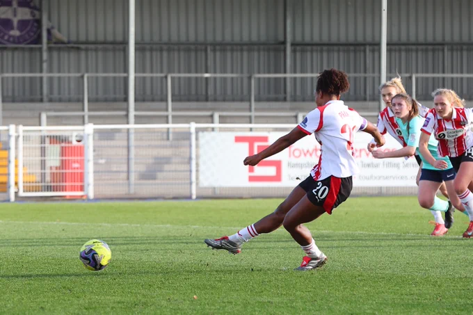 Atlanta Primus scores a penalty against Royston Town, wearing the red and white home kit