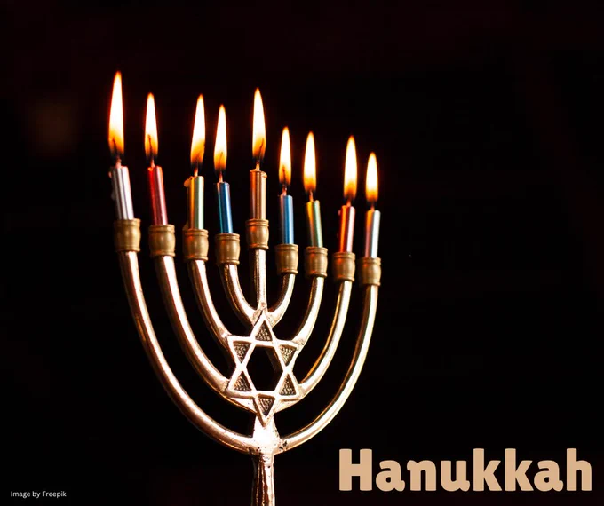 A nine socket candelabrum used during Hanukkah.  It has a central candle socket with four branches either side. Each socket has a lit candle stood in it.