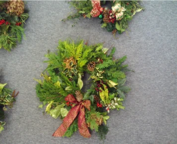 Festive wreath decorated with flowers, foliage, pine cones and red bows