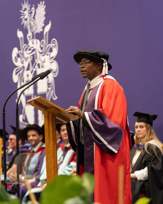 James on stage in a red and purple robe - receiving his award