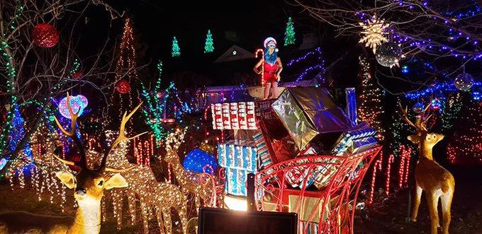 A colorful image of Dr. Gangi's Christmas display, including lights, reindeer, a sled filled with presents, and a mannequin holding a candy cane. 