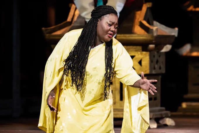 A performer in a yellow robe passionately acting on stage.