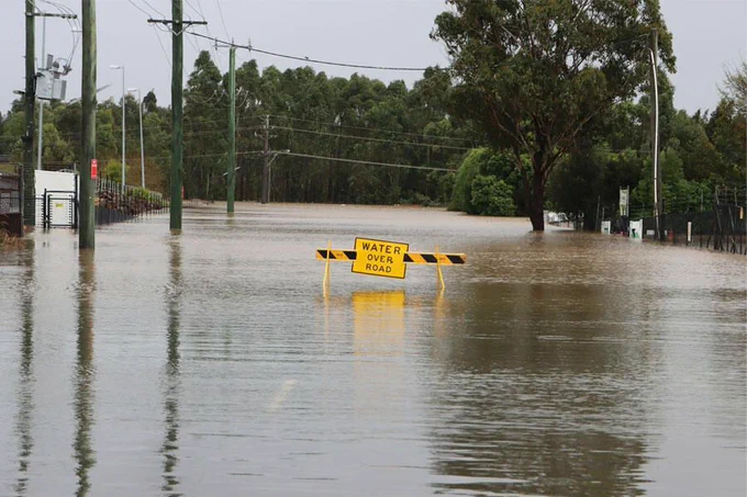 A photo of a warning side on a flooded road, nearly submerged under water