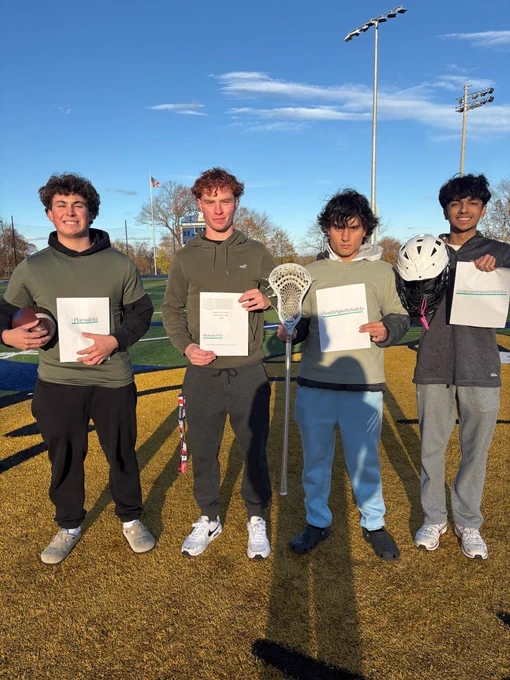 A group of four student athletes hold signs about Injury Prevention Day.