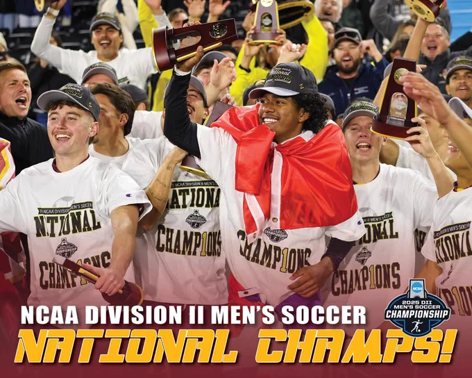 Members of the Midwestern State men’s soccer team celebrate on the field, wearing “National Champions” shirts and hats while raising championship trophies. One player is draped in a red-and-white flag. A graphic overlay reads “National Champs! NCAA Division II Men’s Soccer” with the 2025 DII Men’s Soccer Championship logo.