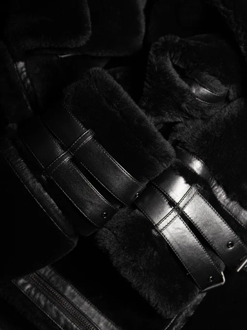 Detailed view of plush black shearling contrasted with smooth leather straps and stitching.