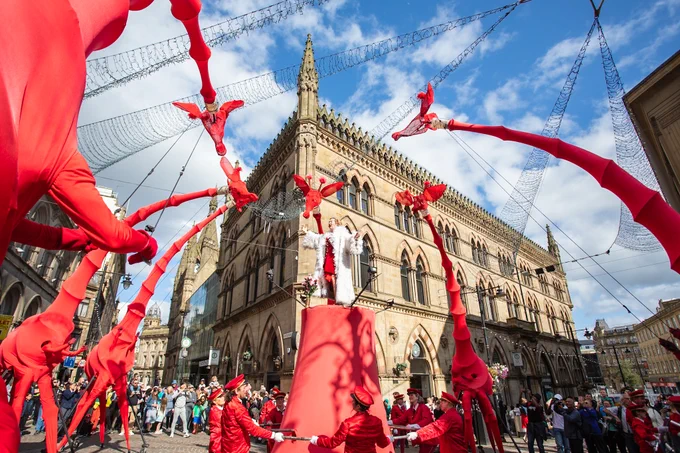 A street performance featuring seven large red giraffe puppets. 