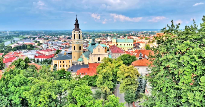 Aerial view of the historic center of Vilnius, Lithuania, featuring Baroque architecture and lush greenery with river in the background.