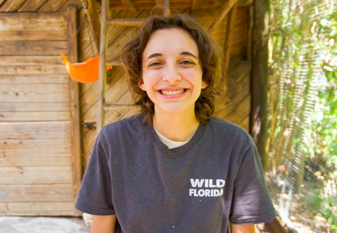 A headshot of Piper, one of the animal care team members at Wild Florida Adventure Park, smiling inside a two-toed sloth exhibit. 