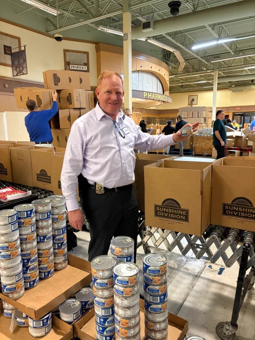 Chief Day stands with cardboard Sunshine boxes and cans of chicken.