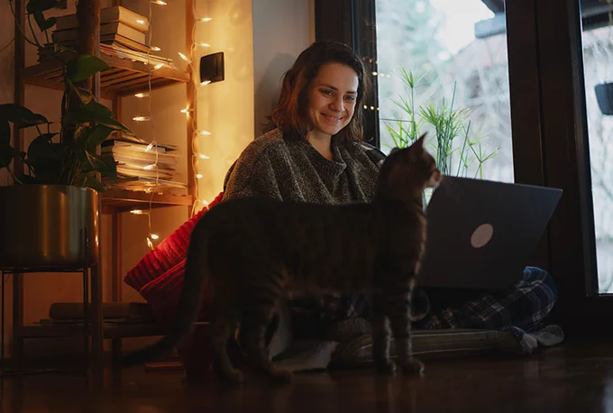 Photograph of a journalist working from their home office with their cat. 