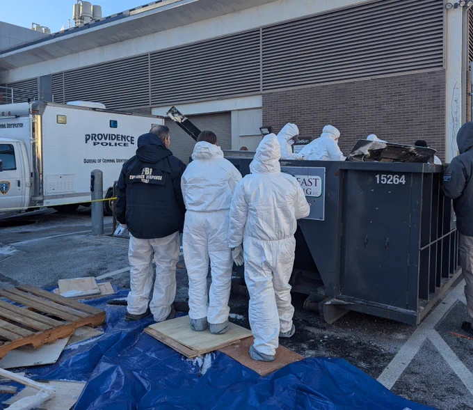 FBI Boston Evidence Response Team examines a large dumpster outside Brown University. A Providence Police crime scene unit vehicle is in the background.