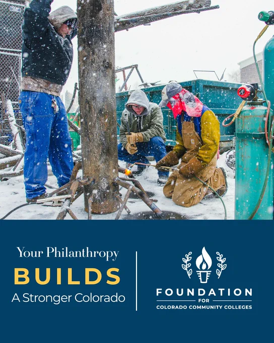 Three people work outdoors in heavy snow, welding and securing metal around a large wooden pole. They wear winter gear and protective clothing. A blue banner at the bottom reads: “Your Philanthropy Builds a Stronger Colorado” with the Foundation for Colorado Community Colleges logo.