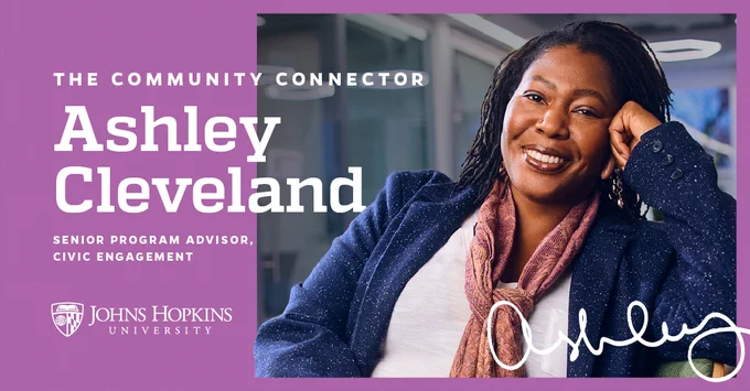 Promotional image featuring Ashley Cleveland, Senior Program Advisor of Civic Engagement at Johns Hopkins University. Ashley is smiling, seated with one hand on their head, in front of a glass paneled backdrop with the text 'The Community Connector' displayed.