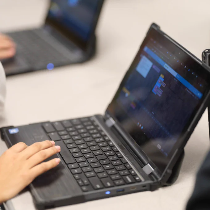 A person using a laptop with a visual programming interface open on the screen, indicating engagement in coding or educational activities.