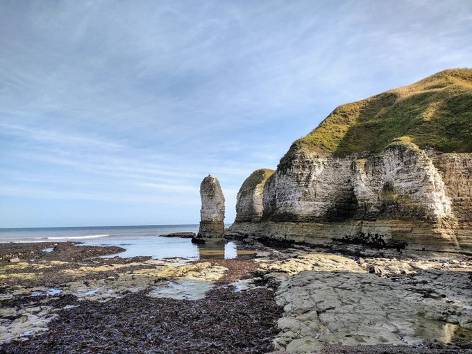 Coastal chalk cliffs in the Yorkshire Wolds (Flamborough Head). The sea is to the left of the image and the cliffs are to the right. There is a stack in the background.