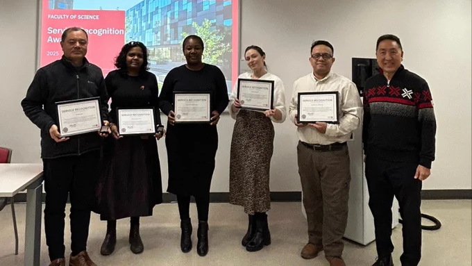 Six people standing in a row, each holding a certificate, in front of a banner that reads "Faculty of Science Service Recognition Awards 2025"