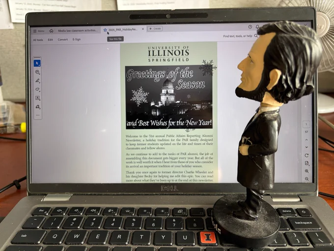 Abe Lincoln bobblehead stands on a laptop keyboard looking at the PAR Alumni newsletter.
