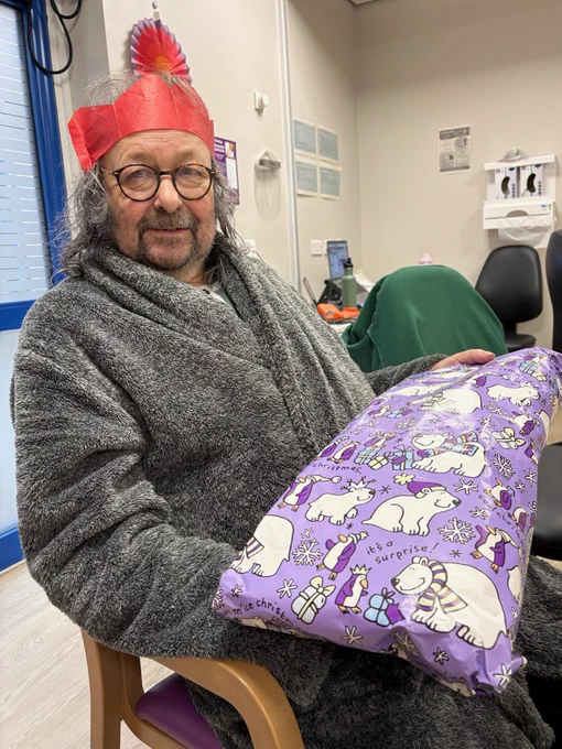 Patient in party hat, with a Christmas present.