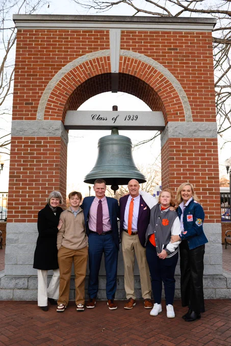 A group of people posing for a photo in front of the Carillon Bell.