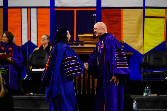 President Clements shaking hands with a student crossing the stage at graduation.