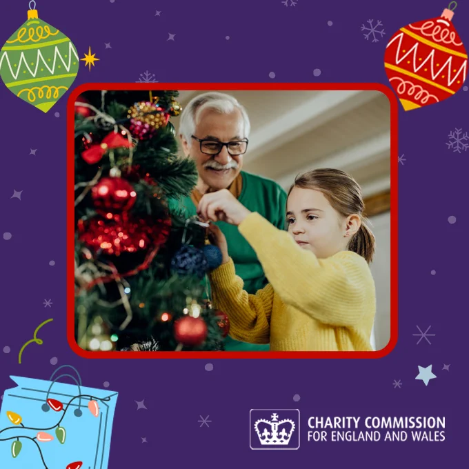 Man and child hanging Christmas tree decorations.