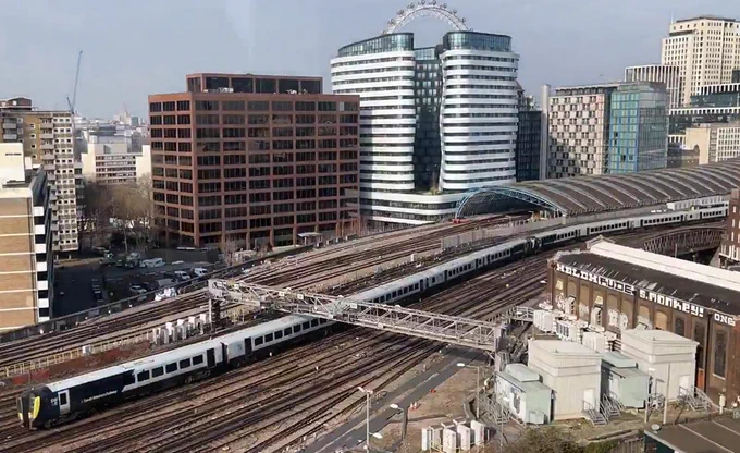 Image of railway lines into London Waterloo station. A train can be seen on the track and buildings including the London Eye in the background.